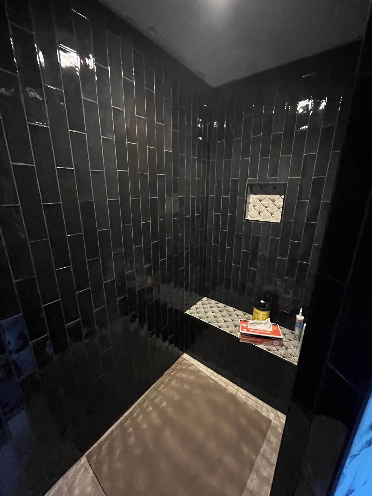 Vertical black tile shower with bench