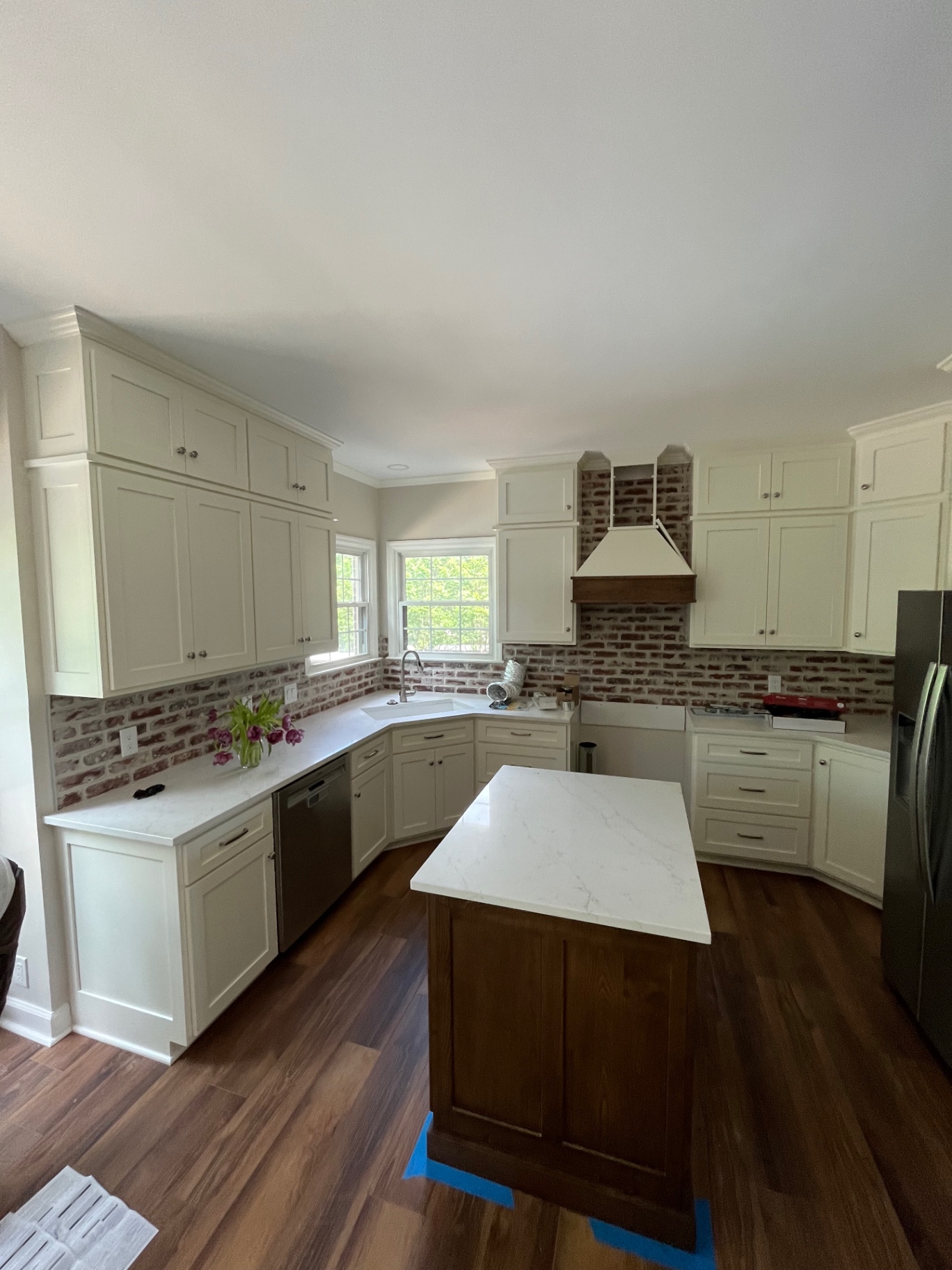White kitchen with brick backsplash & custom hood